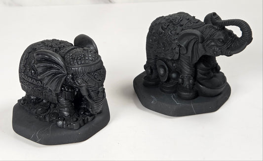 Shungite carving of two elepahants on a white background