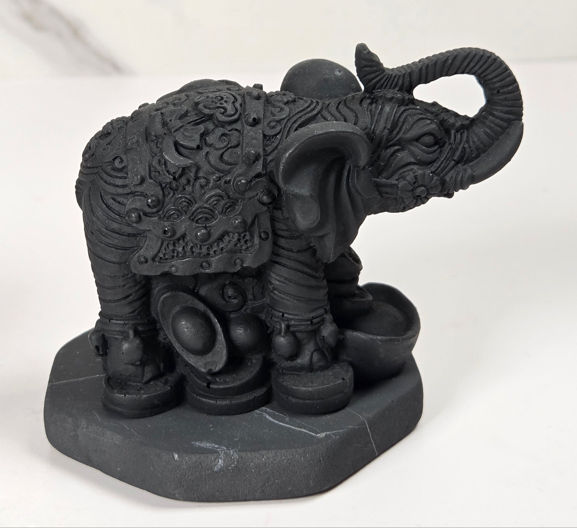Shungite carving of two elepahants on a white background