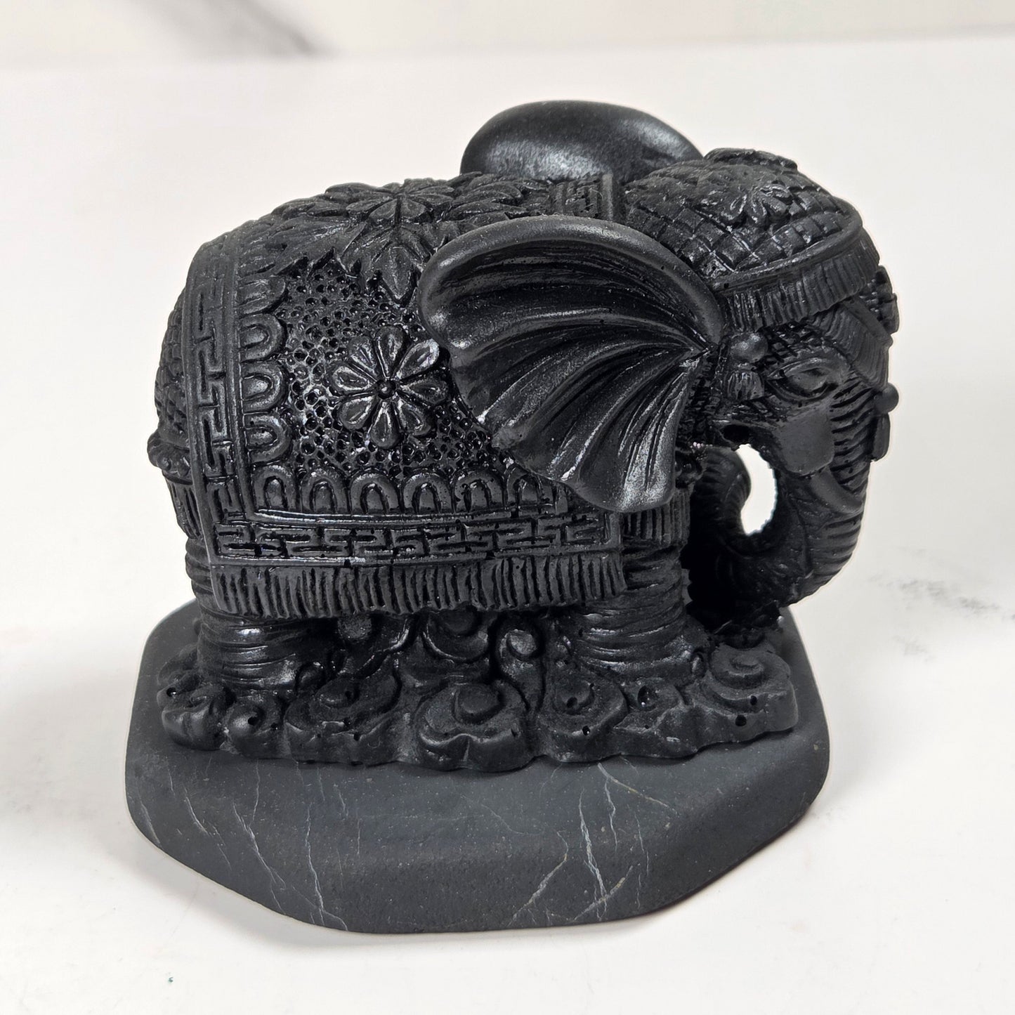 Shungite carving of two elepahants on a white background