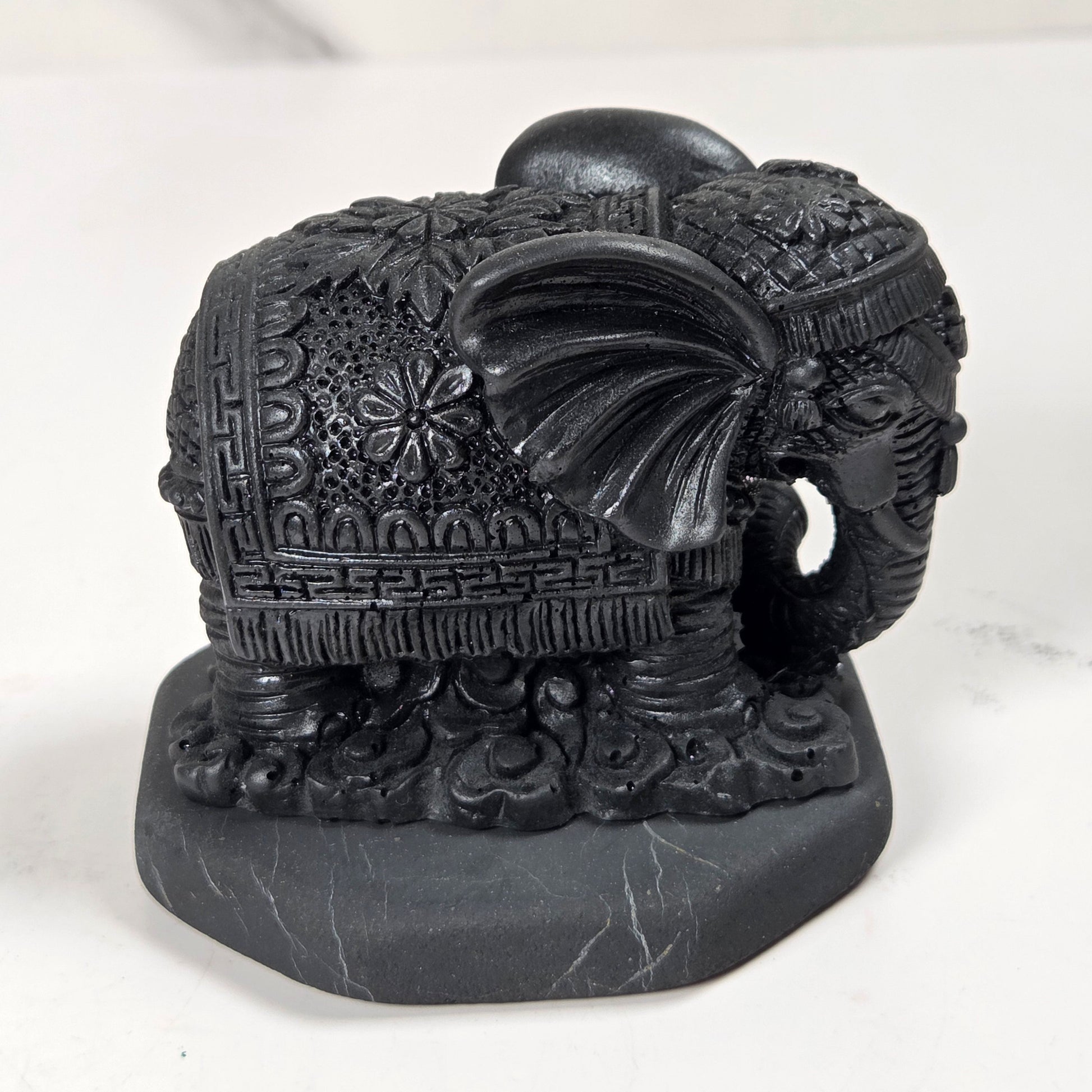 Shungite carving of two elepahants on a white background
