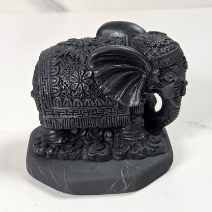 Shungite carving of two elepahants on a white background
