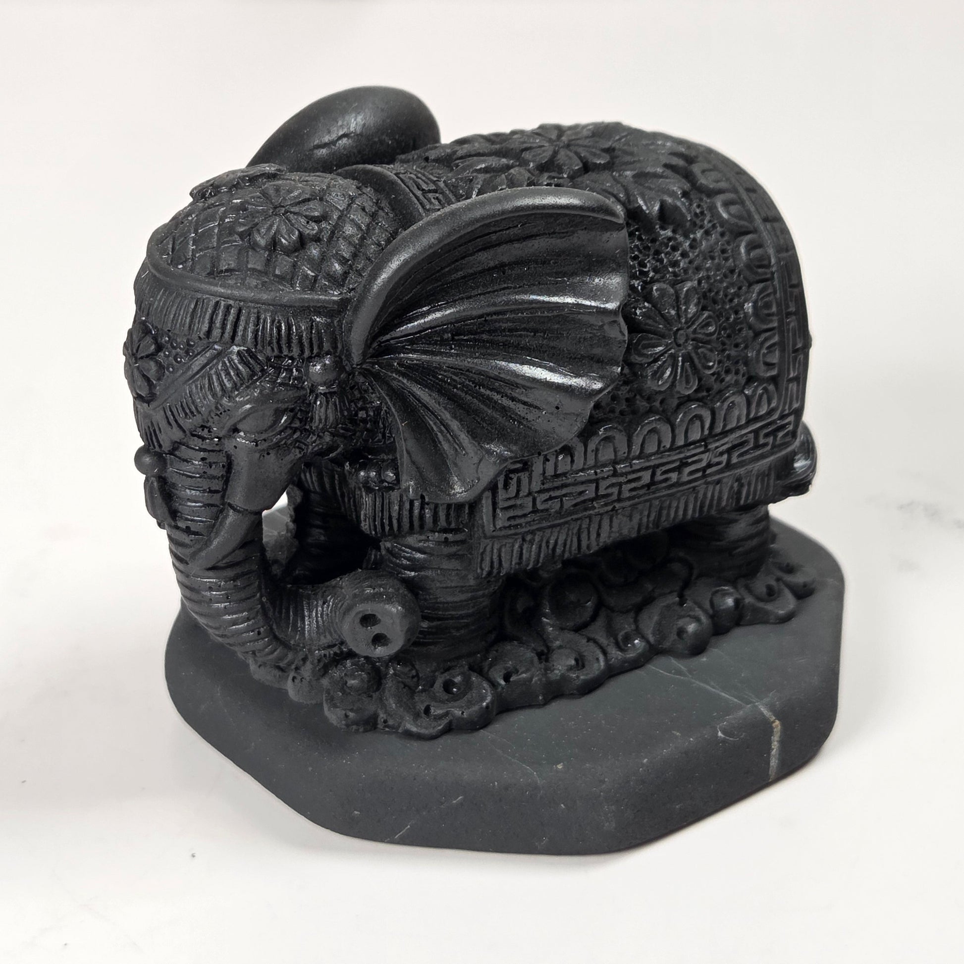 Shungite carving of two elepahants on a white background
