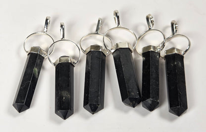 Six black crystal point pendants with silver metal rings and caps, arranged in a row on a plain white background.