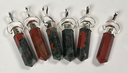 Six faceted crystal pendants with silver-toned metal caps and loops, arranged vertically on a plain white background. The crystals alternate between dark green with red inclusions and reddish-brown with dark inclusions.
