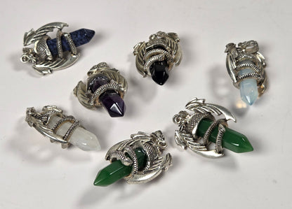 Six silver-toned metal pendant charms featuring wrapped crystal points in various colors, arranged on a plain white surface.