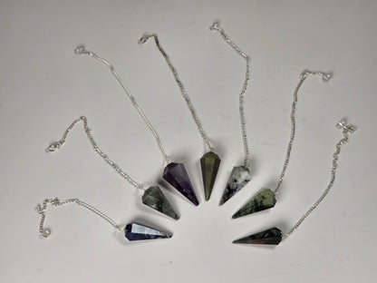 Six silver-toned cone pendants with different colored gemstone tips arranged in a fan shape on a plain light background.