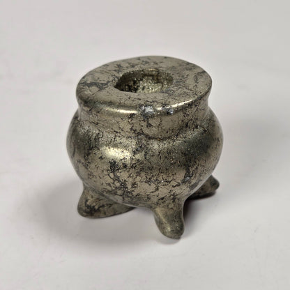 A small antique silver metal censer or incense burner with a textured, weathered finish, standing on three short legs against a plain light gray background.