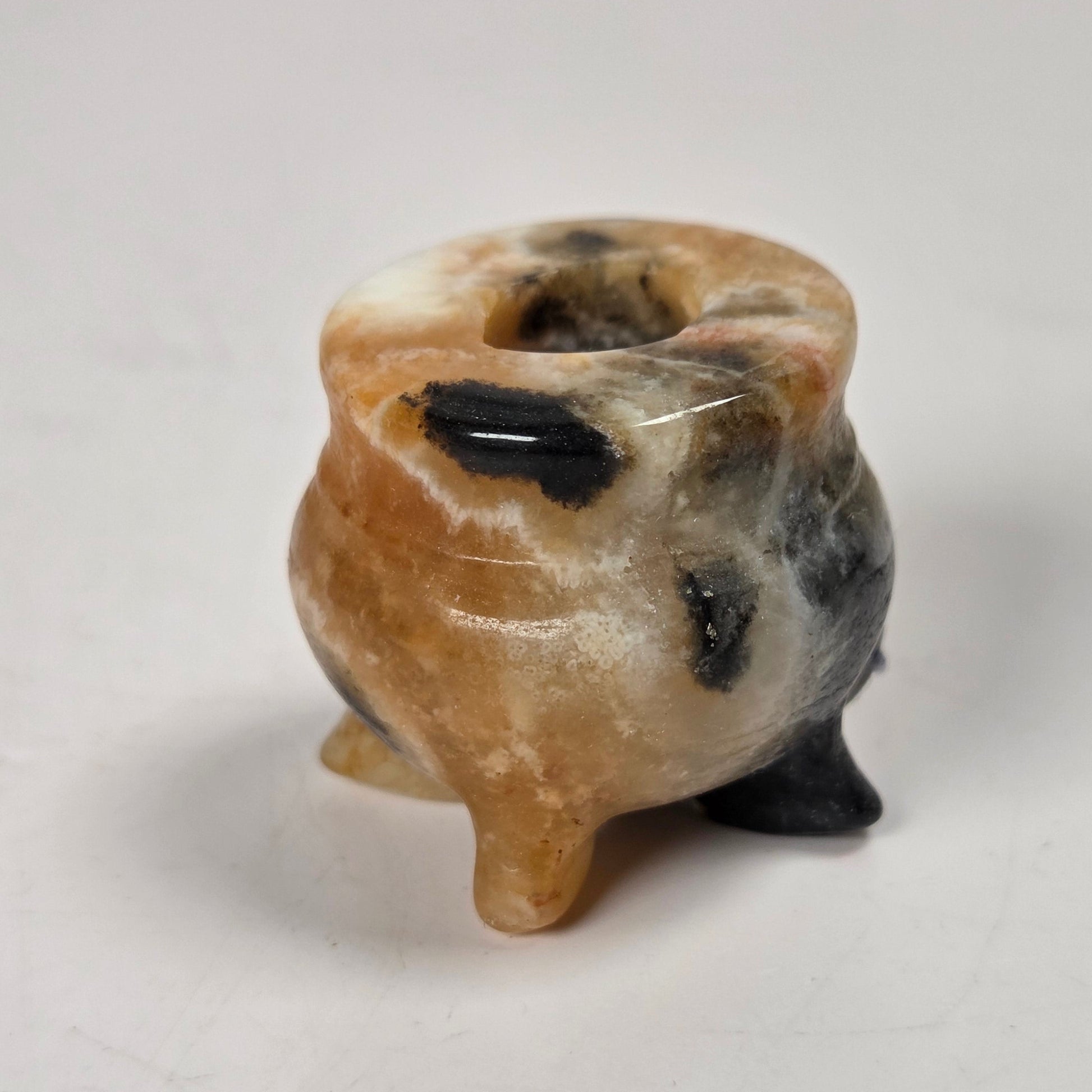 small cauldron carving with orange and block coloring against a white background