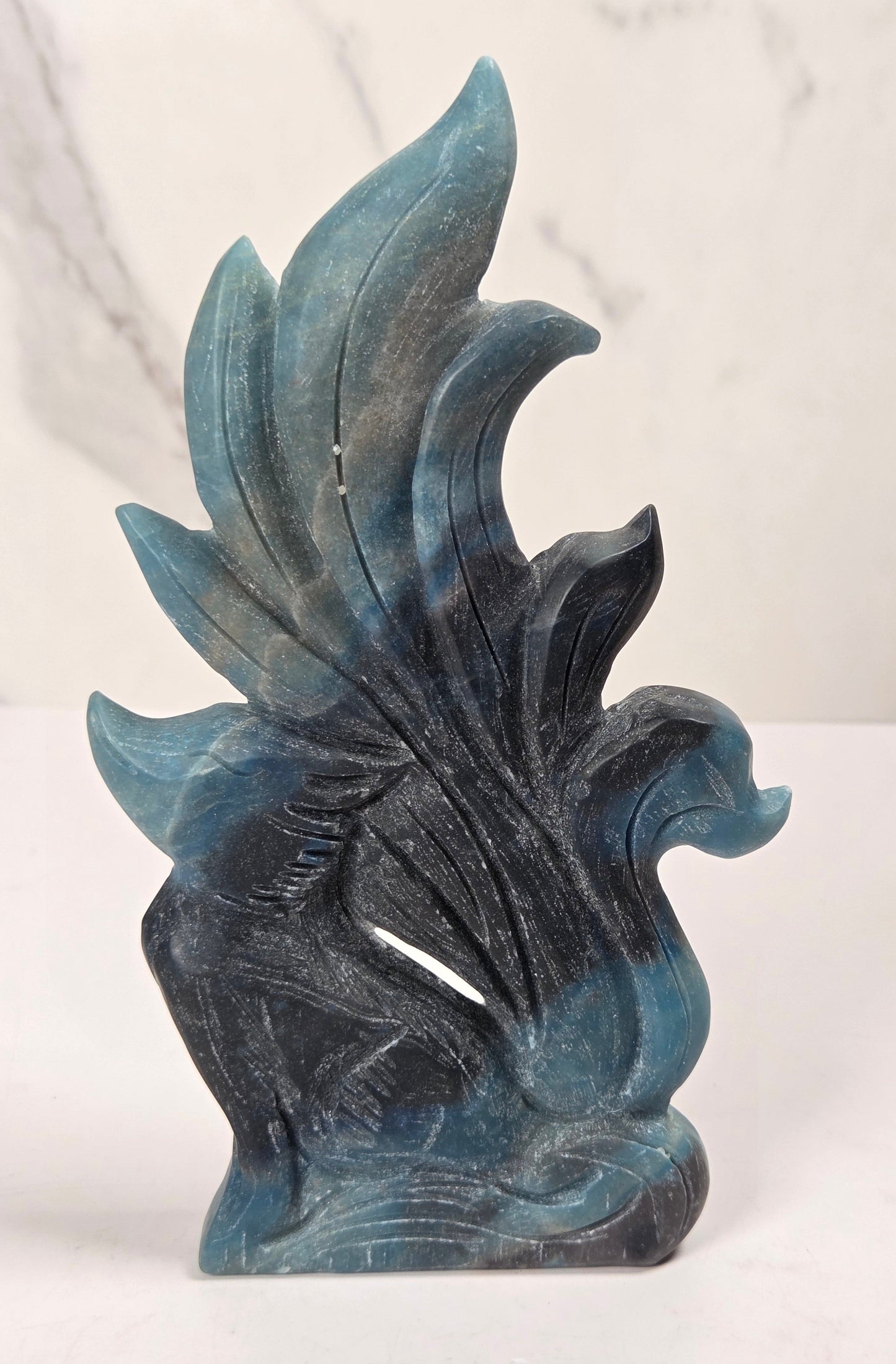 Crystal carving of a 9 tail fox made of trolleite with blue and black coloring on a white background