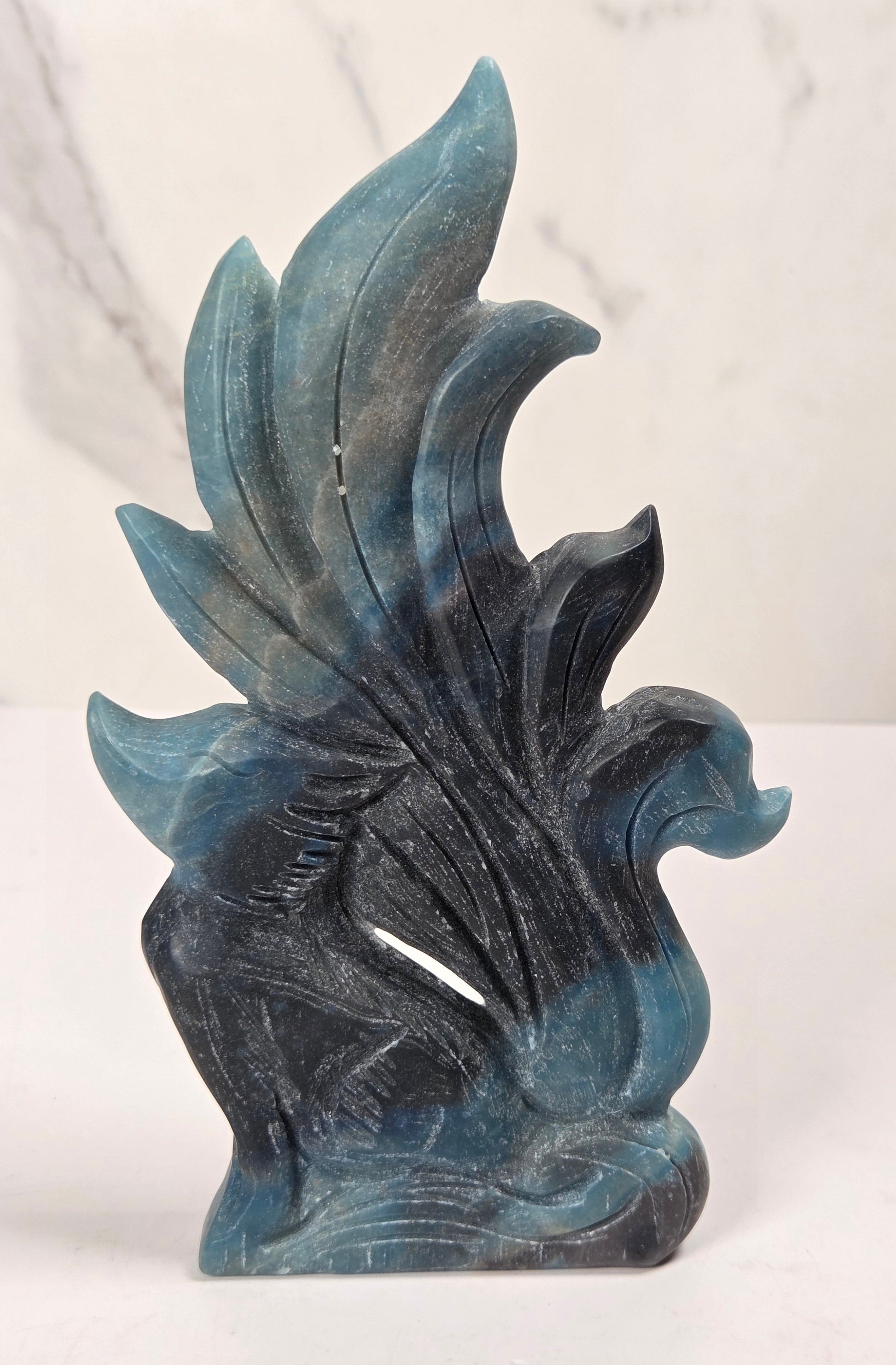 Crystal carving of a 9 tail fox made of trolleite with blue and black coloring on a white background