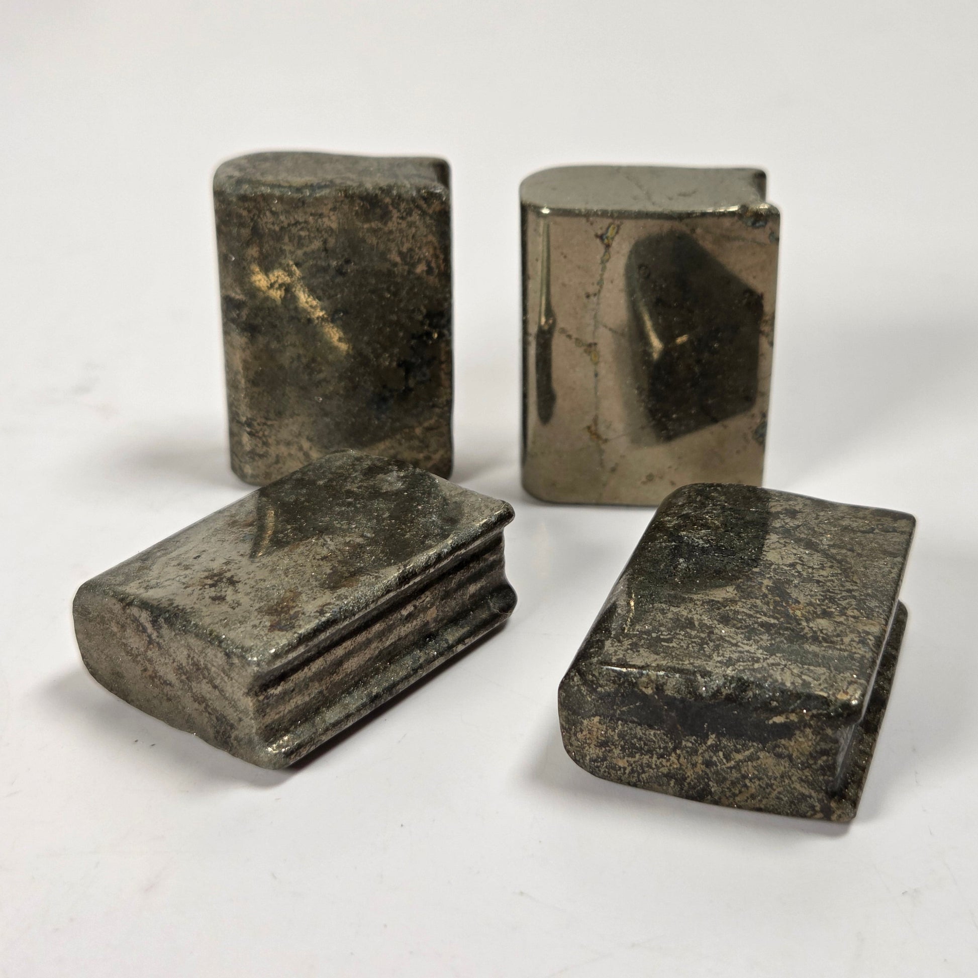 Four small metallic rectangular objects with rounded corners, shown on a plain light background. Two stand upright and two lie flat, with a weathered silver-gray metallic finish.