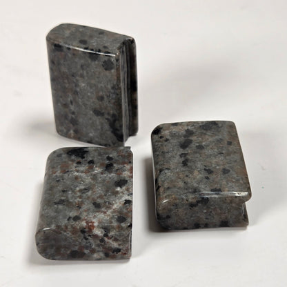 Three polished rectangular stone blocks with a speckled dark gray and black granite pattern, arranged on a plain white surface.