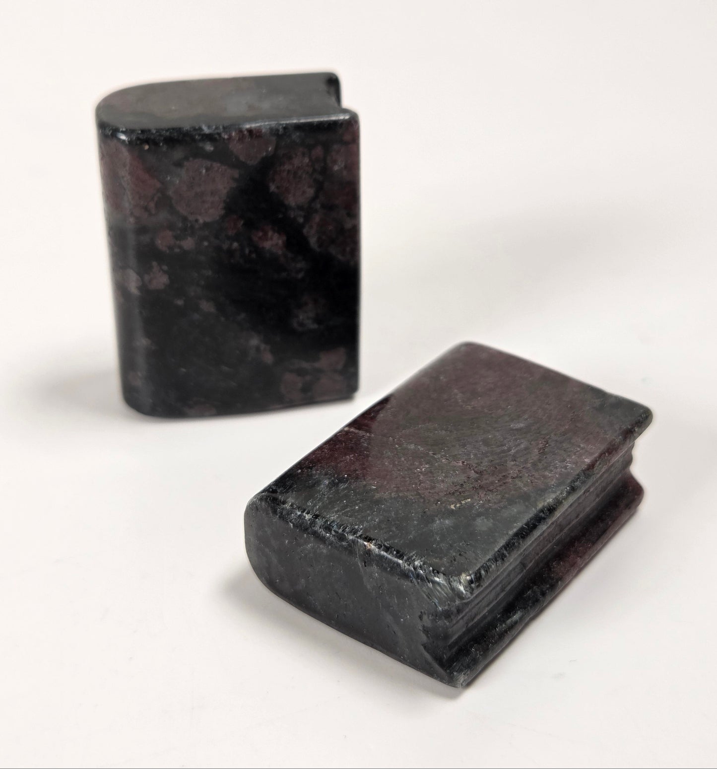Two small rectangular dark stone objects with a mottled black and reddish-brown marbled pattern, photographed on a plain white background.