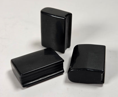 Three glossy black rectangular hard cases or boxes arranged on a plain light background.