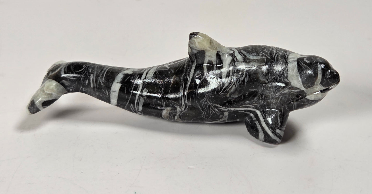 A polished black and white marbled stone dolphin figurine, displayed on a plain light gray background.