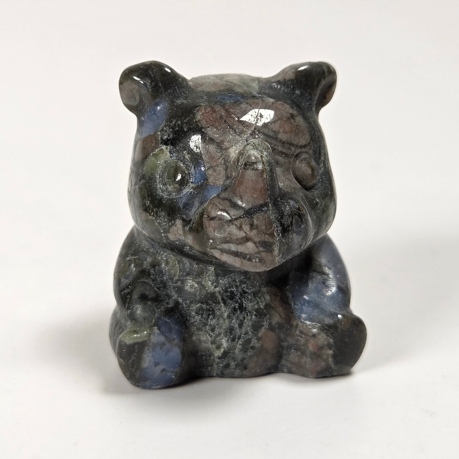 A small carved figurine of a bear, made from polished labradorite stone with natural blue, gray, and brown inclusions, set against a plain white background.