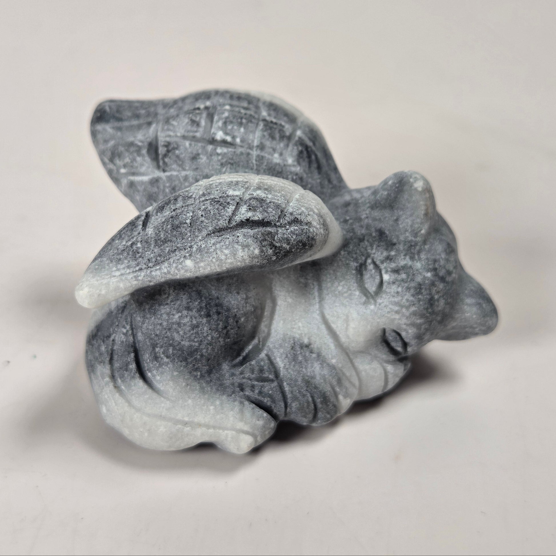 A small gray stone angel figurine with wings and a halo, shown on a plain light background.