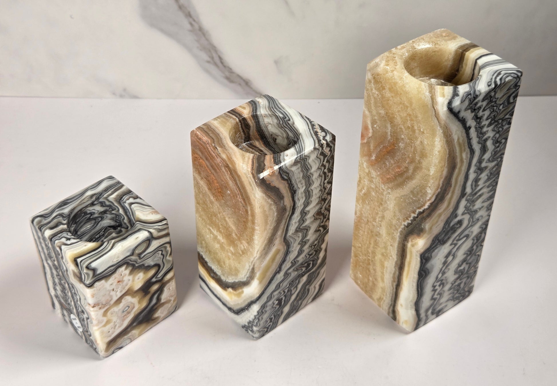Set of 3 zebra calcite candle holders of varying size with bands of orange, black and white against a white background