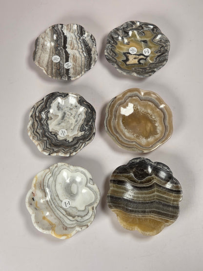 Six small decorative bowls made from patterned agate or marble, arranged in two columns of three on a light gray background. Each bowl has a unique natural stone pattern in shades of gray, black, white, beige, and brown, with small white labels showing numbers like 101, 102, and 103.