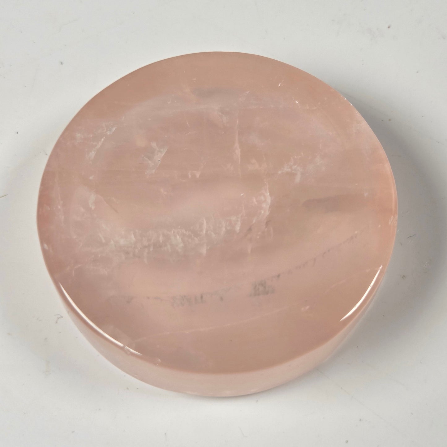 A round, polished pink stone slab or decorative piece on a light gray background.