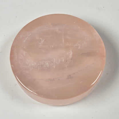 A round, polished pink stone slab or decorative piece on a light gray background.