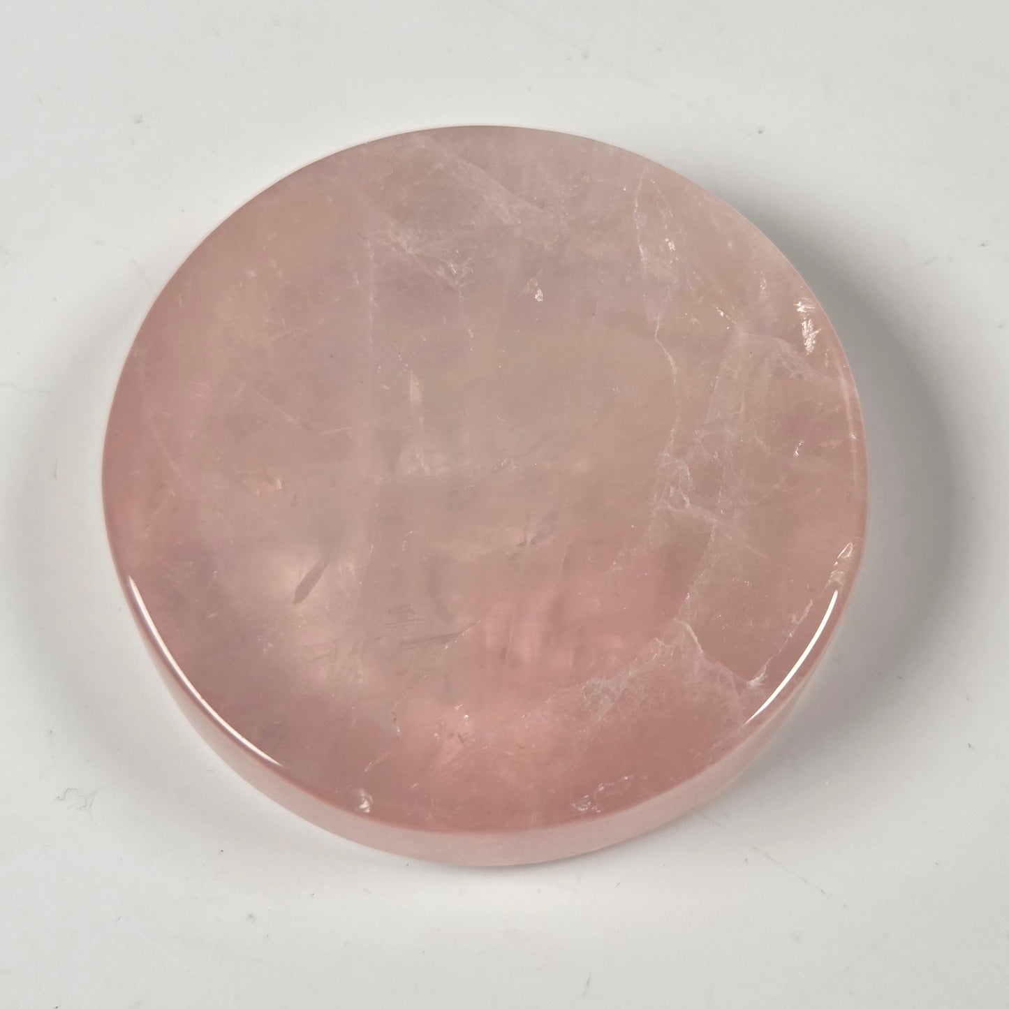 A round, polished pink stone cabochon with natural marbling, displayed on a neutral light gray background.