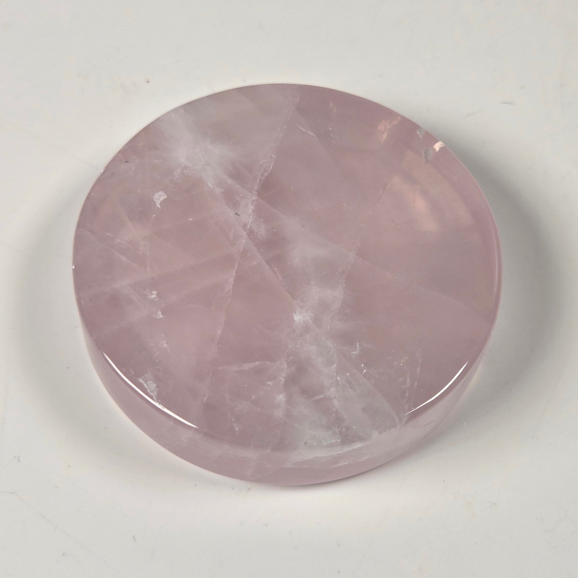 A round, polished pink stone cabochon with natural white veining, displayed on a neutral off-white background.