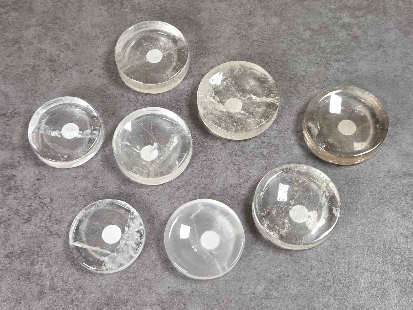 Collection of clear quartz disc shaped carvings on a dark background