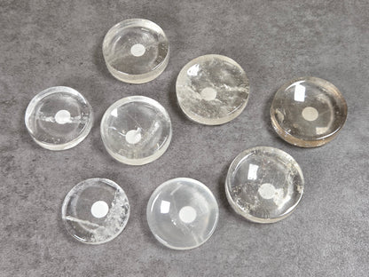 Collection of clear quartz disc shaped carvings on a dark background