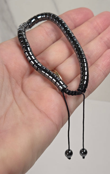 A black beaded bracelet with a sliding cord closure and small bead ends, shown resting on an open hand.