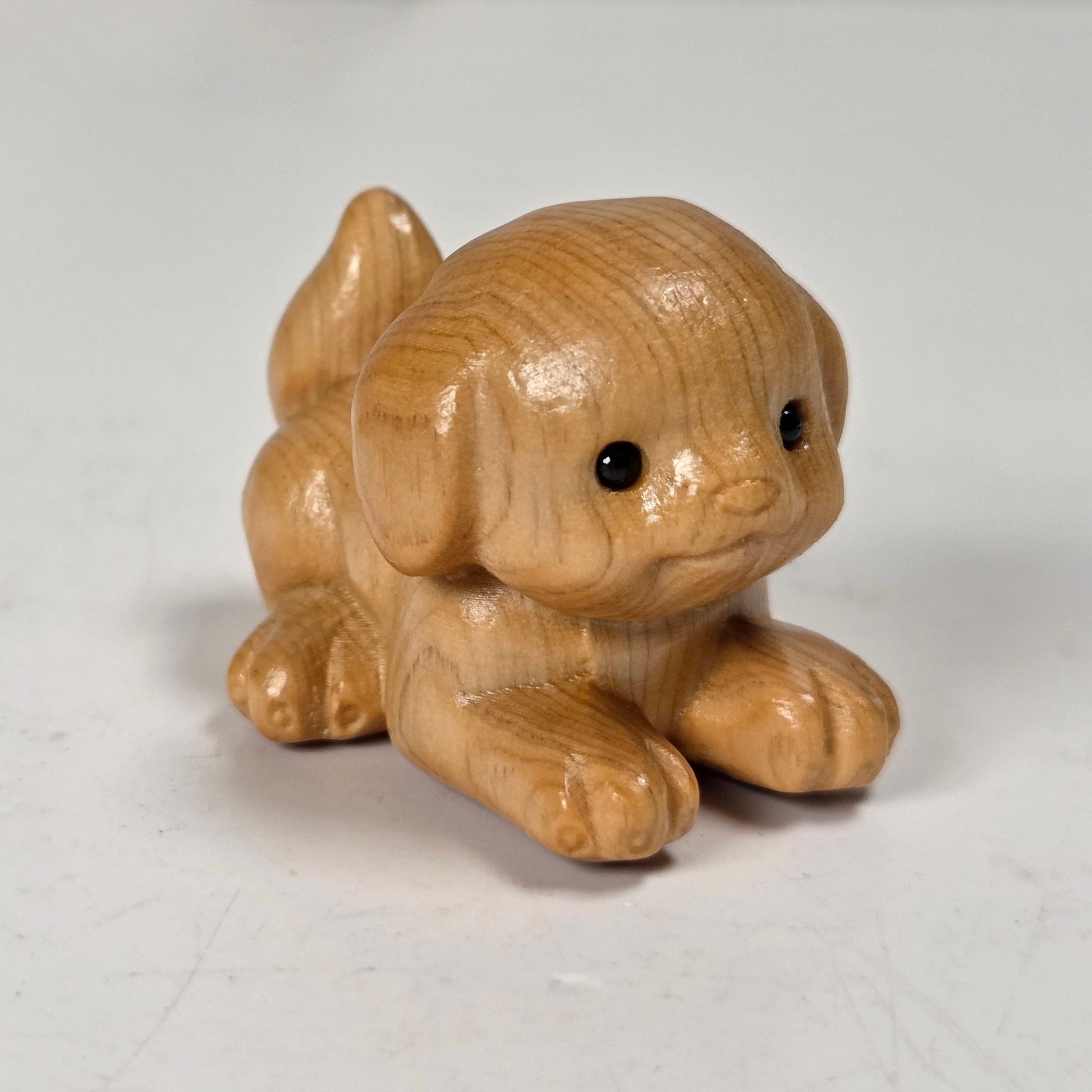 A small hand-carved wooden dog figurine with a glossy finish, positioned on a light gray surface.
