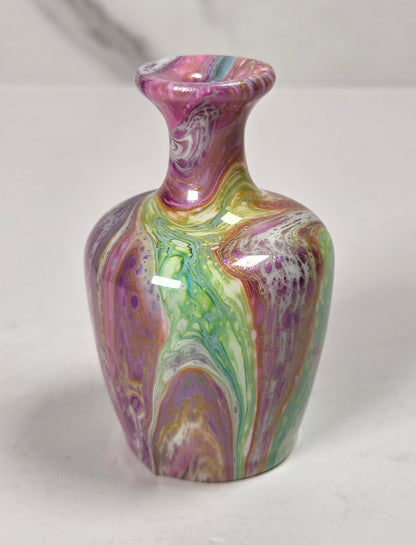 A small decorative vase with a glossy marbled pattern in purple, pink, green, and gold, set against a light gray background.