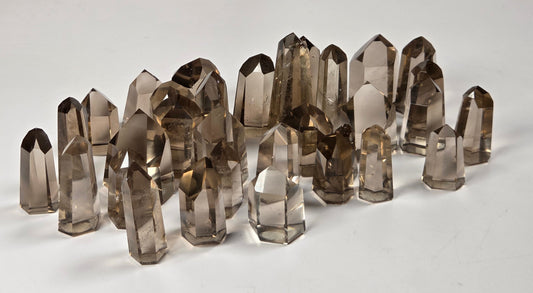 A group of smoky quartz crystal points arranged on a white surface with a light gray marble-patterned background.
