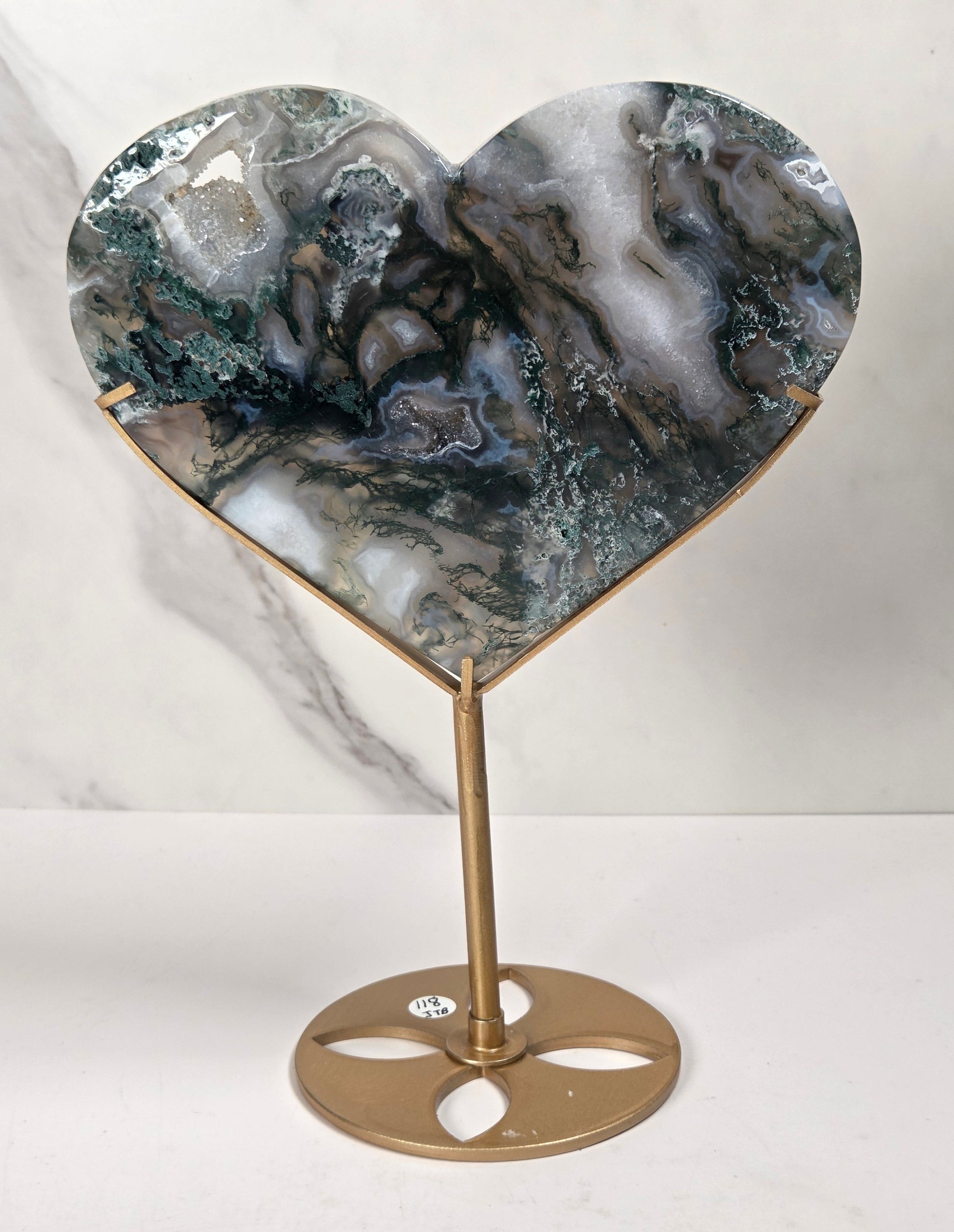 Heart-shaped tabletop carving with a polished agate stone face in green, gray, and white marbled patterns, mounted on a gold-finished metal stand with a circular base.