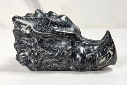 A polished black and white marbled stone object with a sculpted, organic surface, photographed on a light neutral background.
