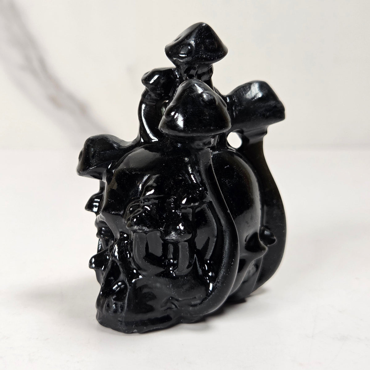 A glossy black carved figurine depicting a rider on a horse, photographed on a light gray surface with a soft gray background.