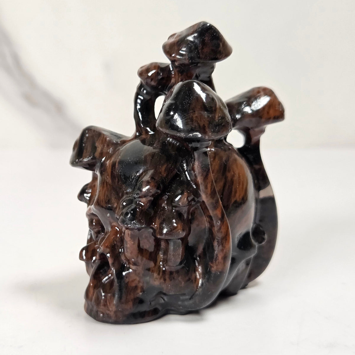 A small carved dark brown wooden figurine depicting a rider on a horse, photographed on a light gray and white marble-patterned surface.