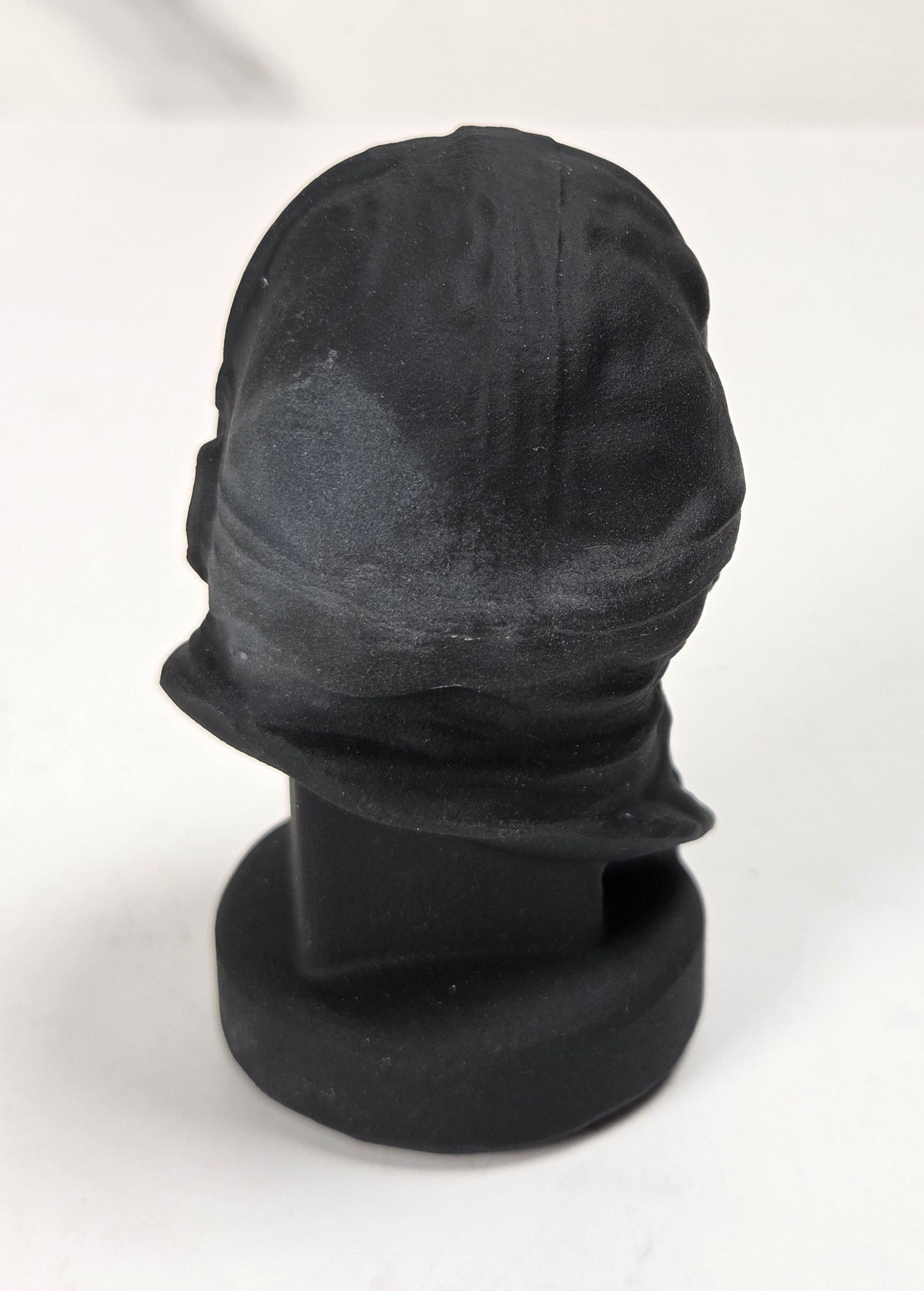A black baseball cap displayed on a black mannequin head stand against a white background.