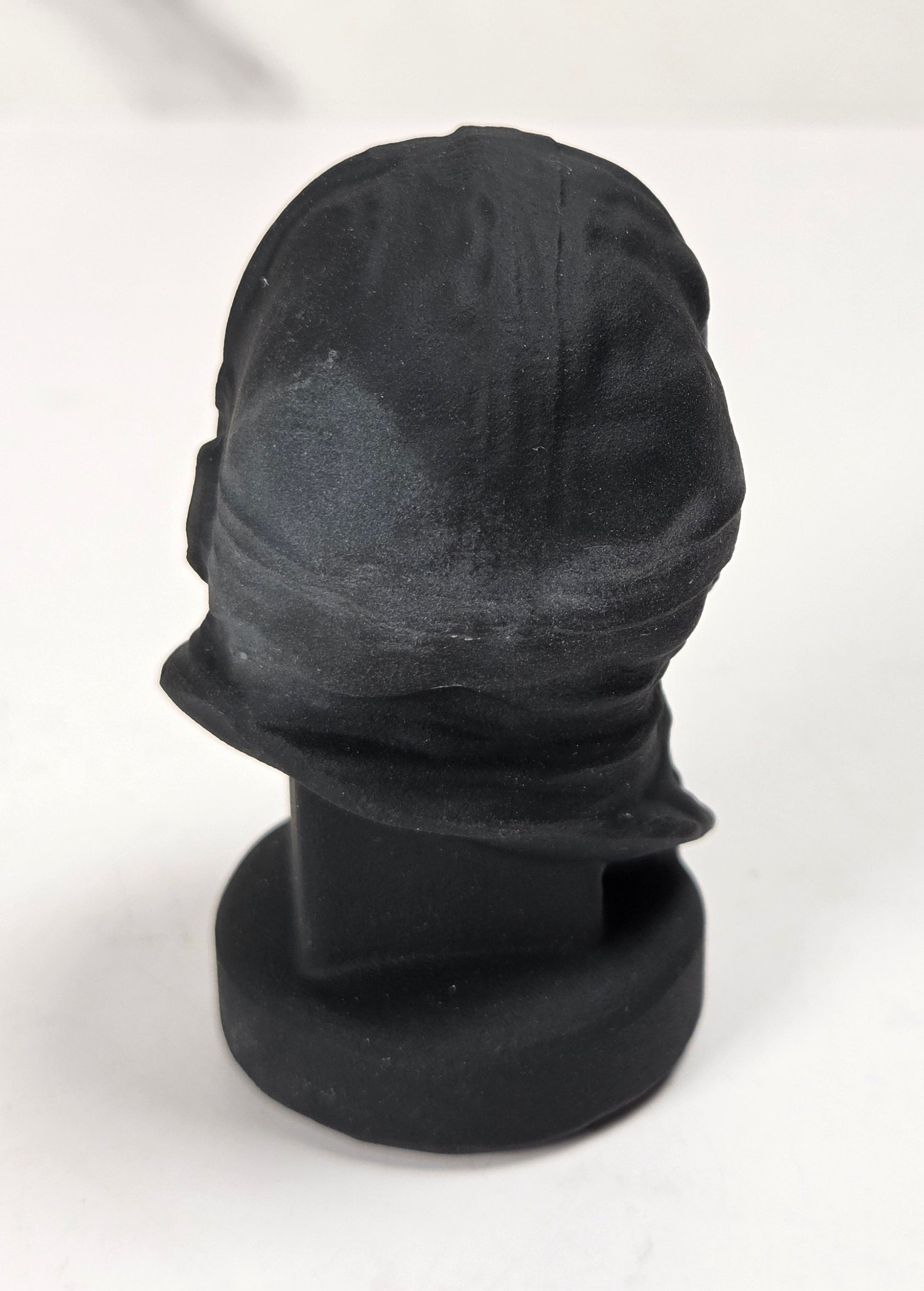 A black baseball cap displayed on a black mannequin head stand against a white background.