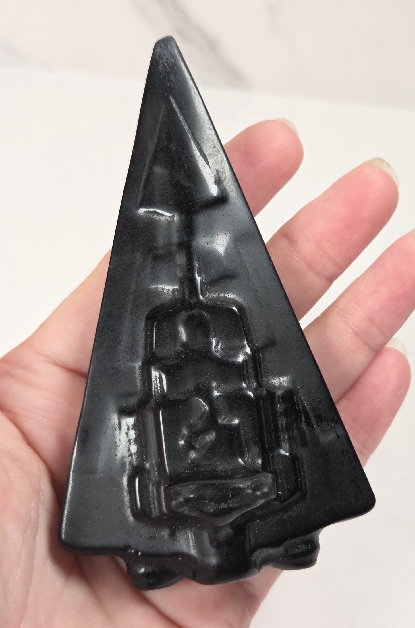 Hand holding an Obsidian carving of a Star Wars ship on a white background