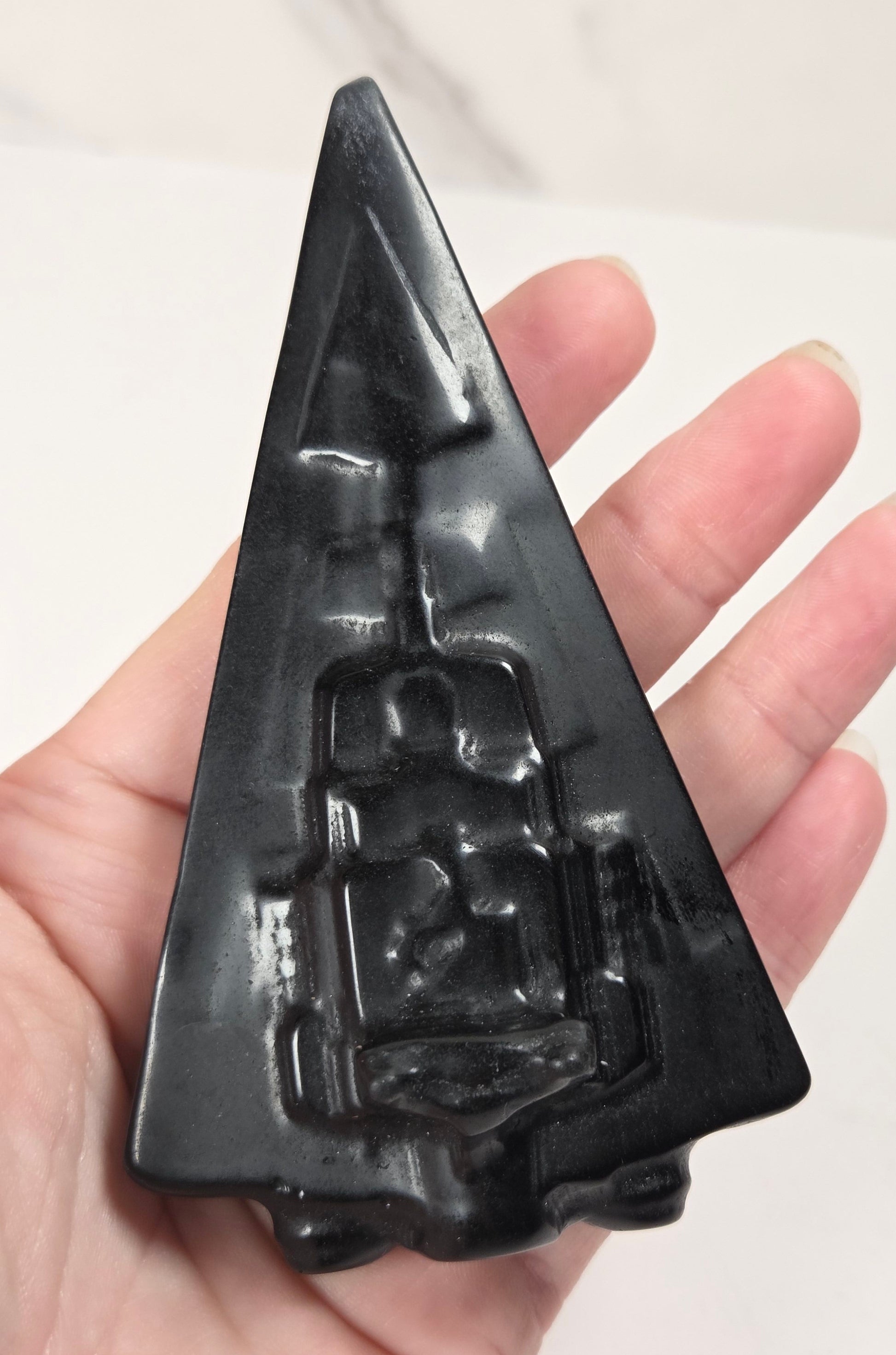 Hand holding an Obsidian carving of a Star Wars ship on a white background