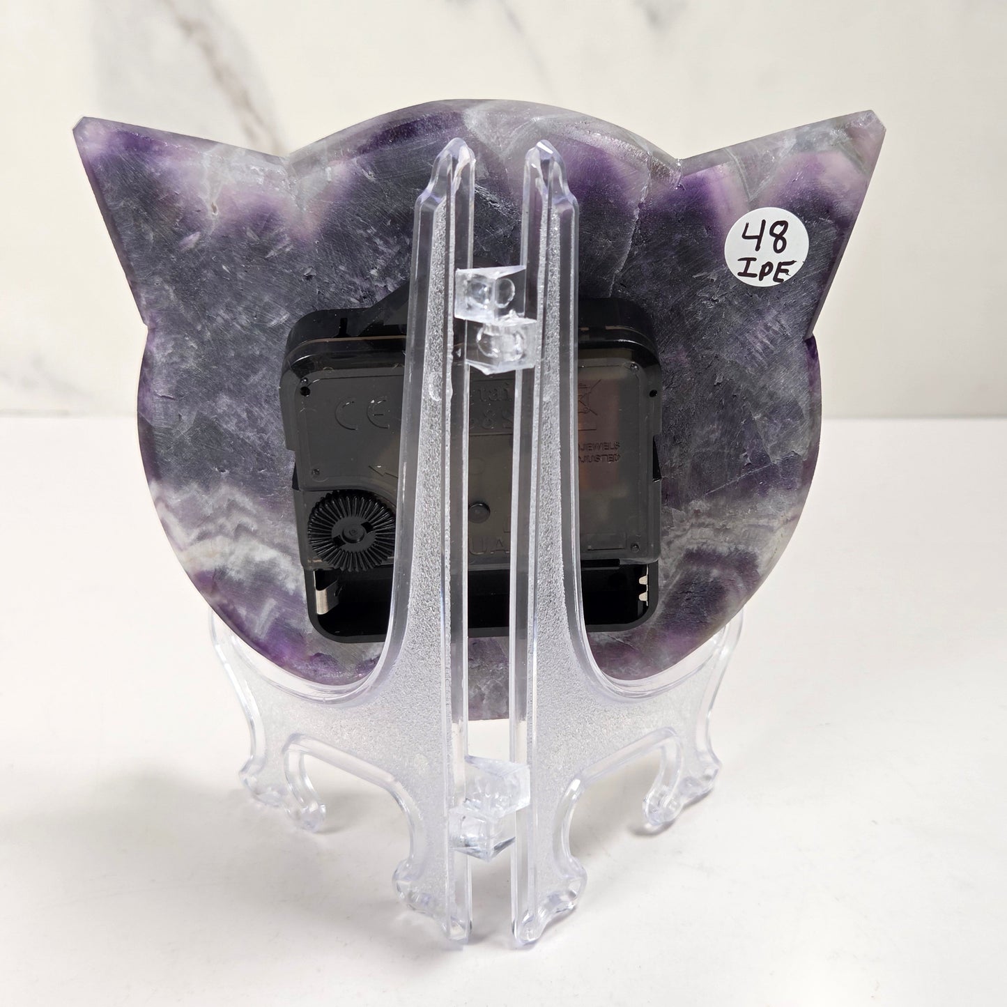 A cat-shaped picture frame made of purple and white marbled stone, displayed on a clear acrylic stand against a white marble-patterned background.