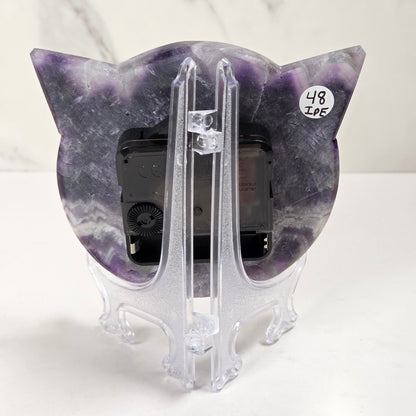 A cat-shaped picture frame made of purple and white marbled stone, displayed on a clear acrylic stand against a white marble-patterned background.