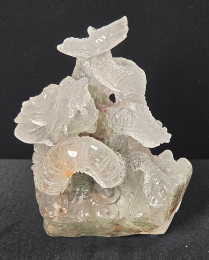 A carved translucent stone sculpture depicting a stylized dragon coiled over lotus flowers, set against a dark black background.