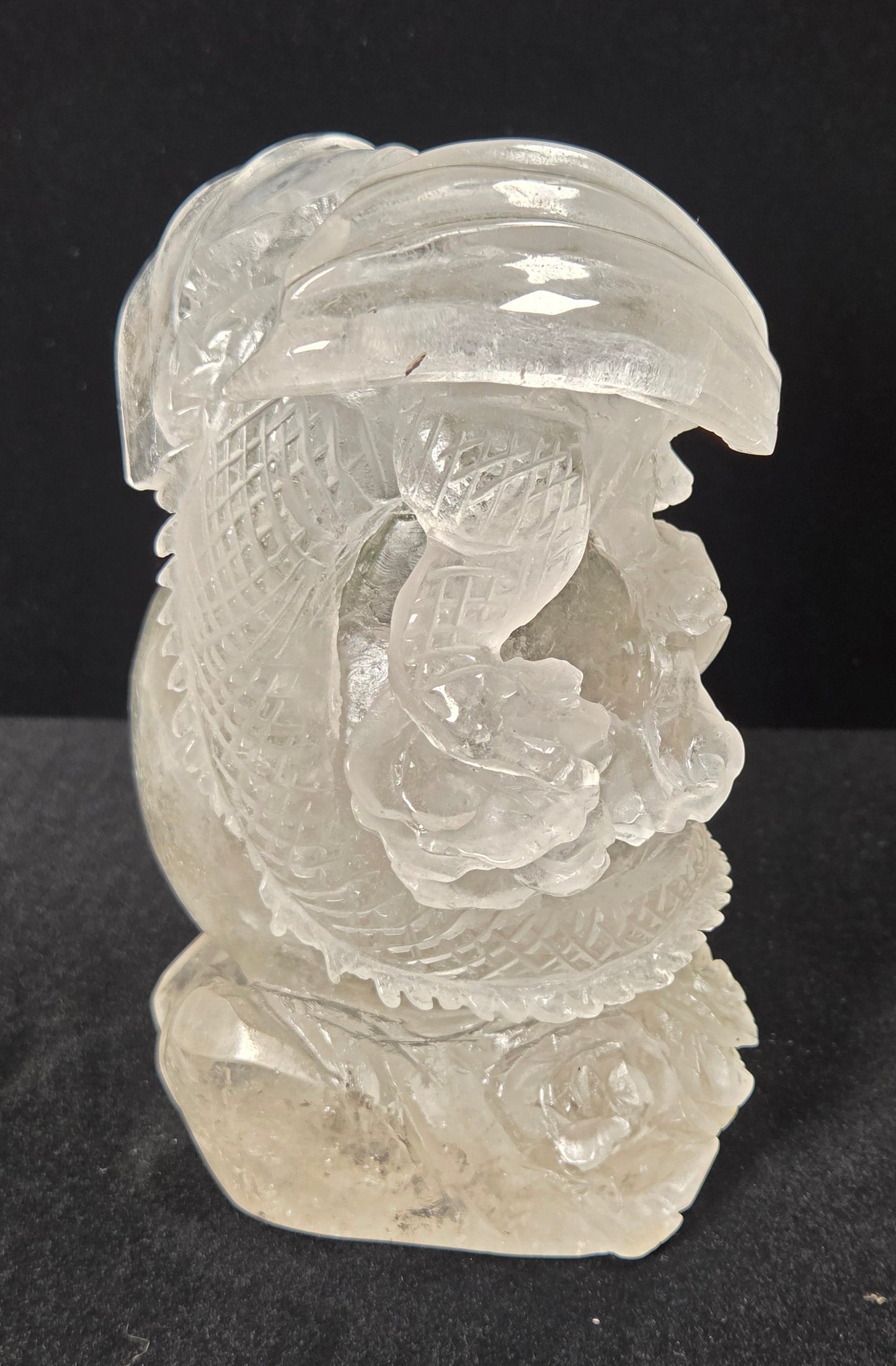 A carved clear crystal dragon figurine, showcasing detailed engravings and polished facets, set against a solid black background.