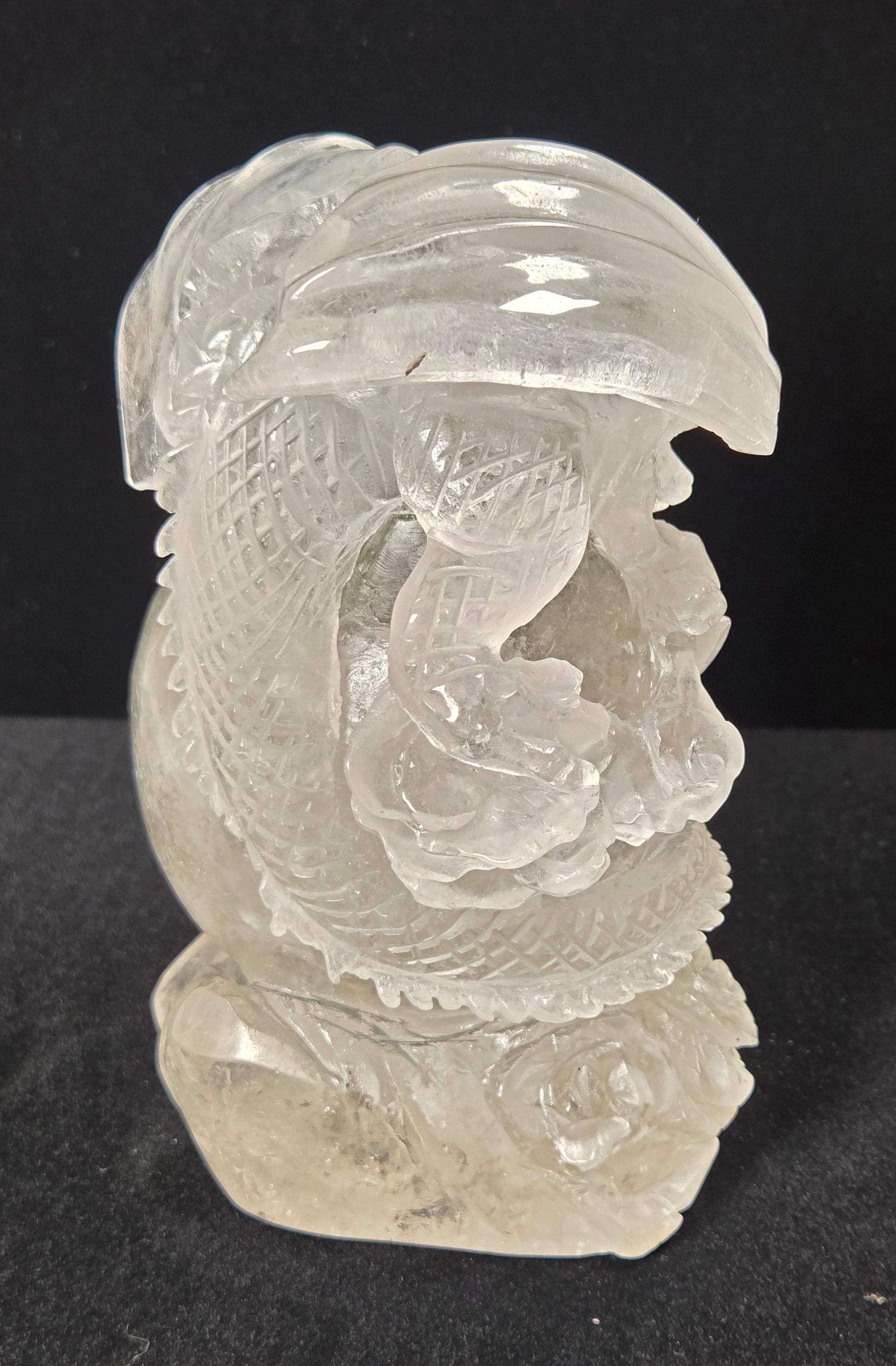 A carved clear crystal dragon figurine, showcasing detailed engravings and polished facets, set against a solid black background.