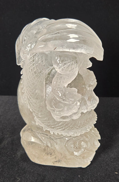 A carved clear crystal dragon figurine, showcasing detailed engravings and polished facets, set against a solid black background.