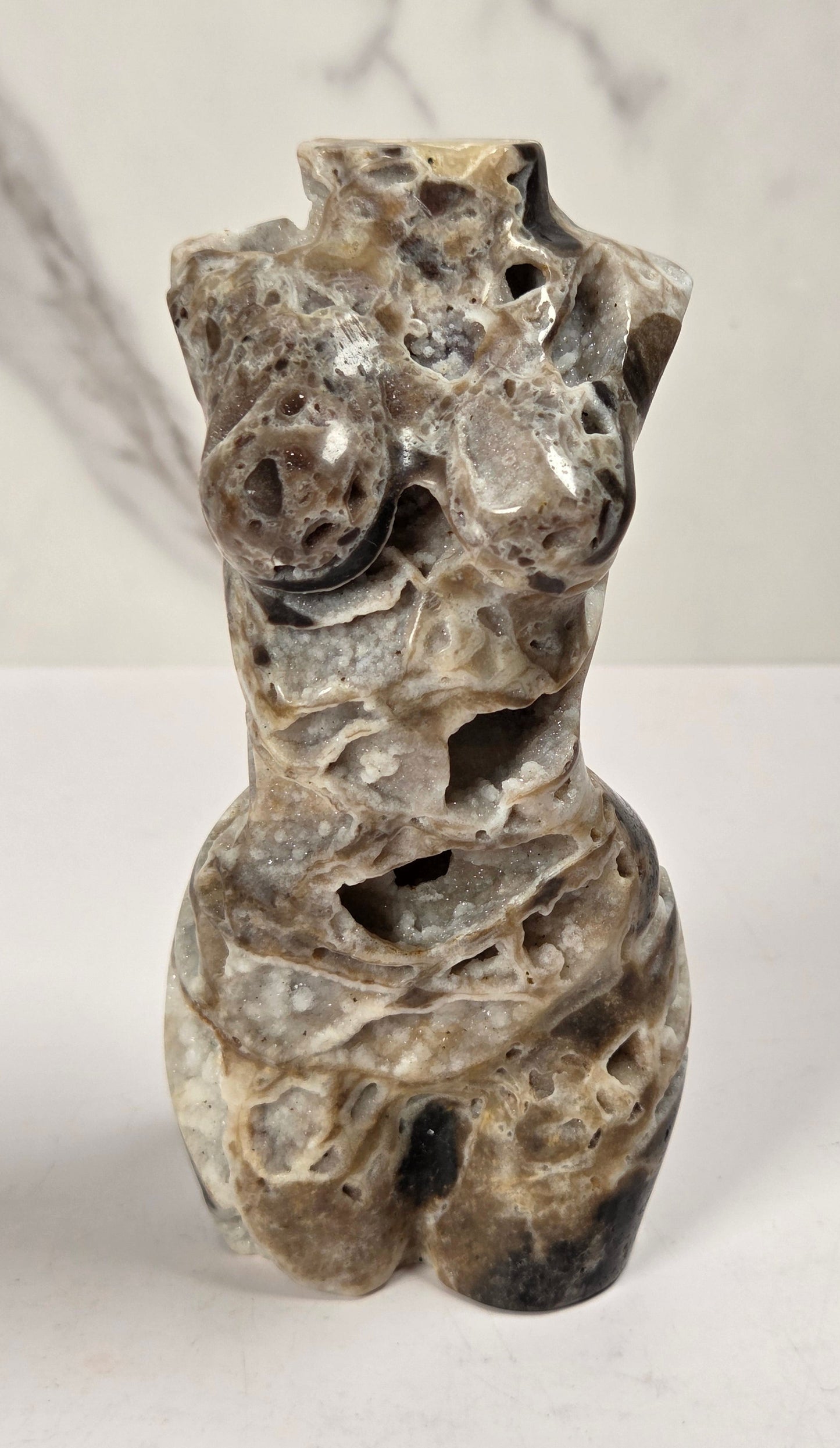 Druzy quartz carved female torso against a white background
