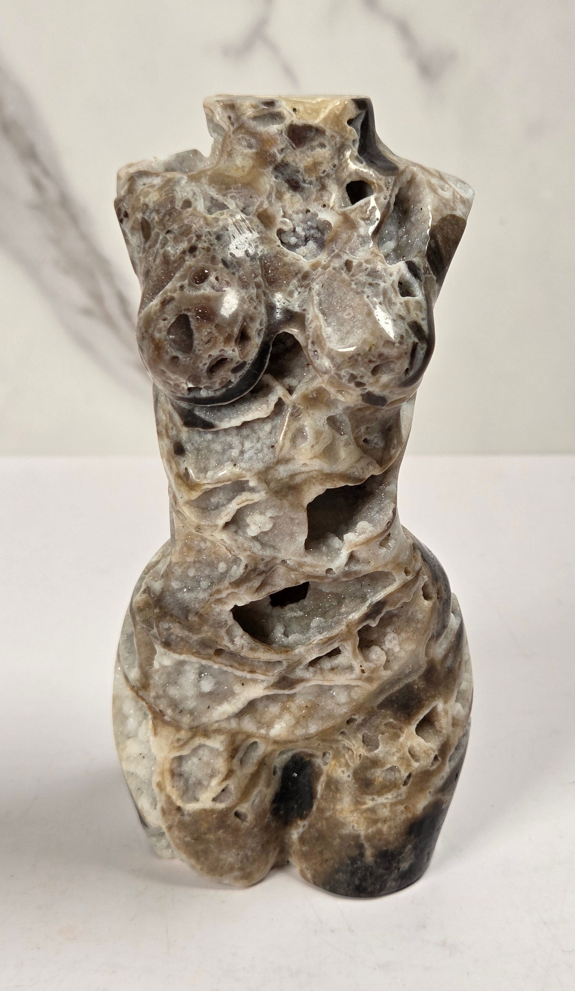 Druzy quartz carved female torso against a white background