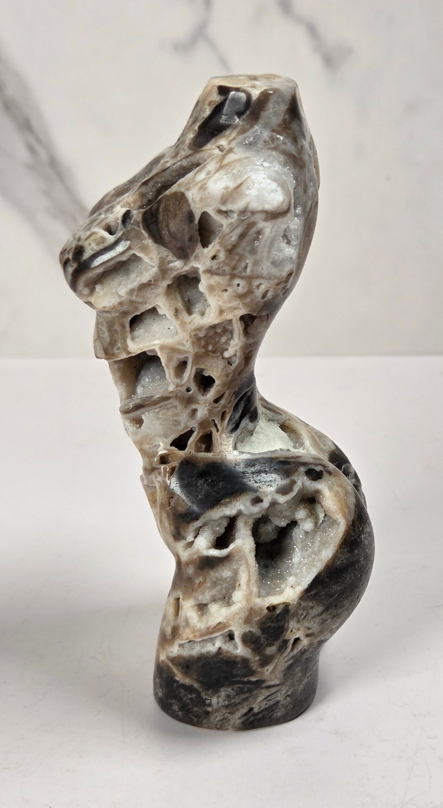 Druzy quartz carved female torso against a white background